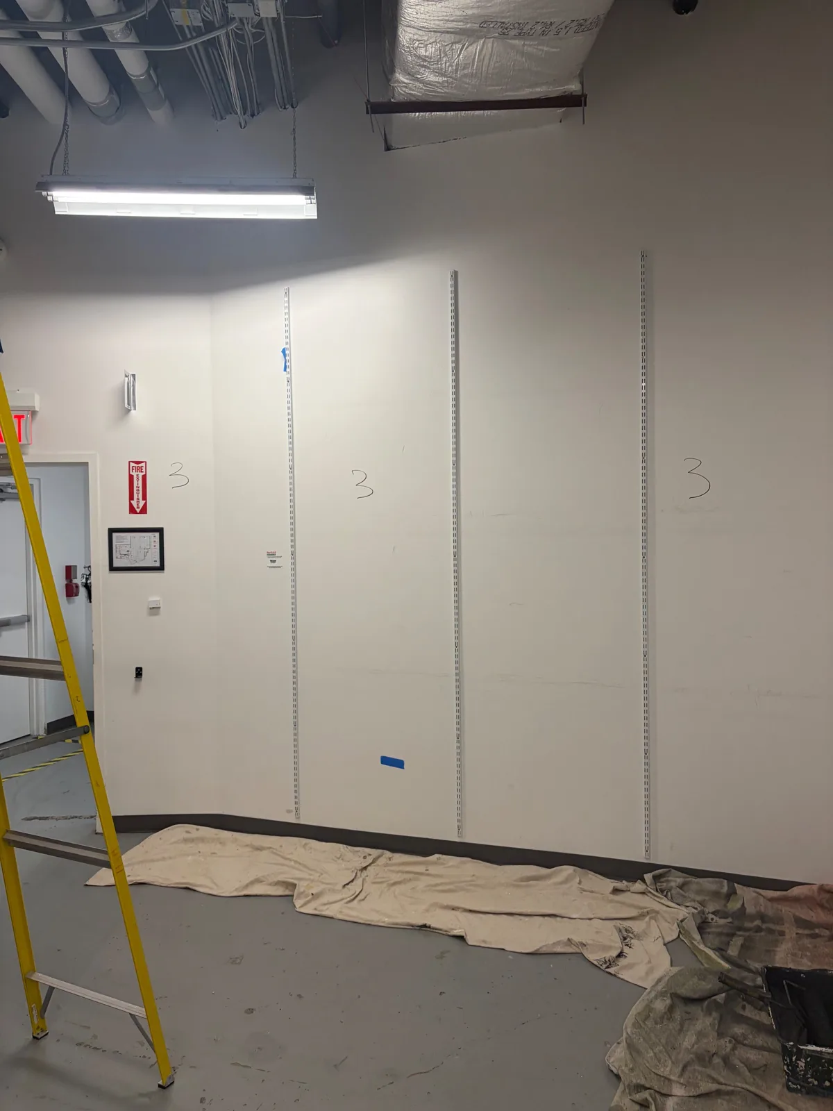 Drop cloths laid along a stockroom wall before painting