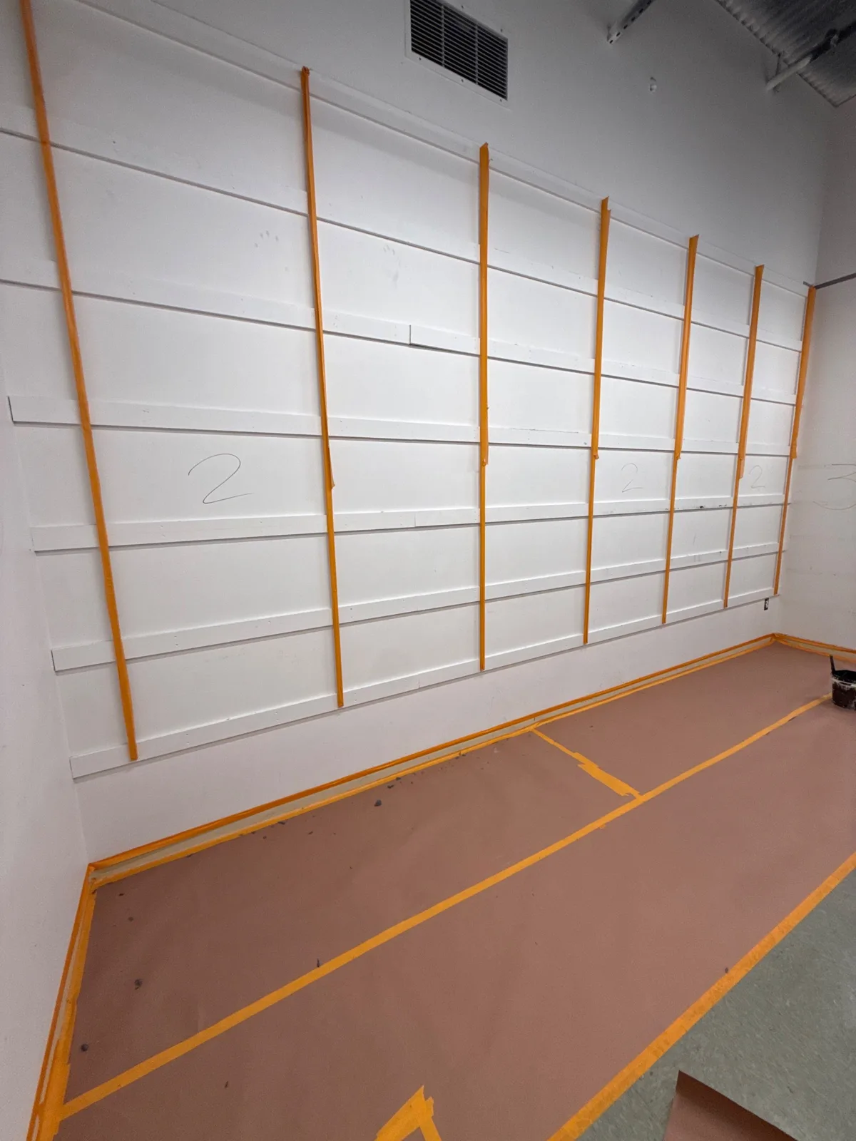 Stockroom wall taped and floor protected before coating